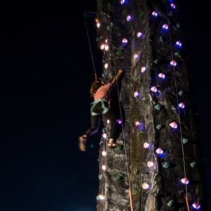 Girl climbing rock wall at night