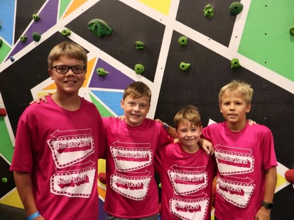Boys posing next to a climbing wall